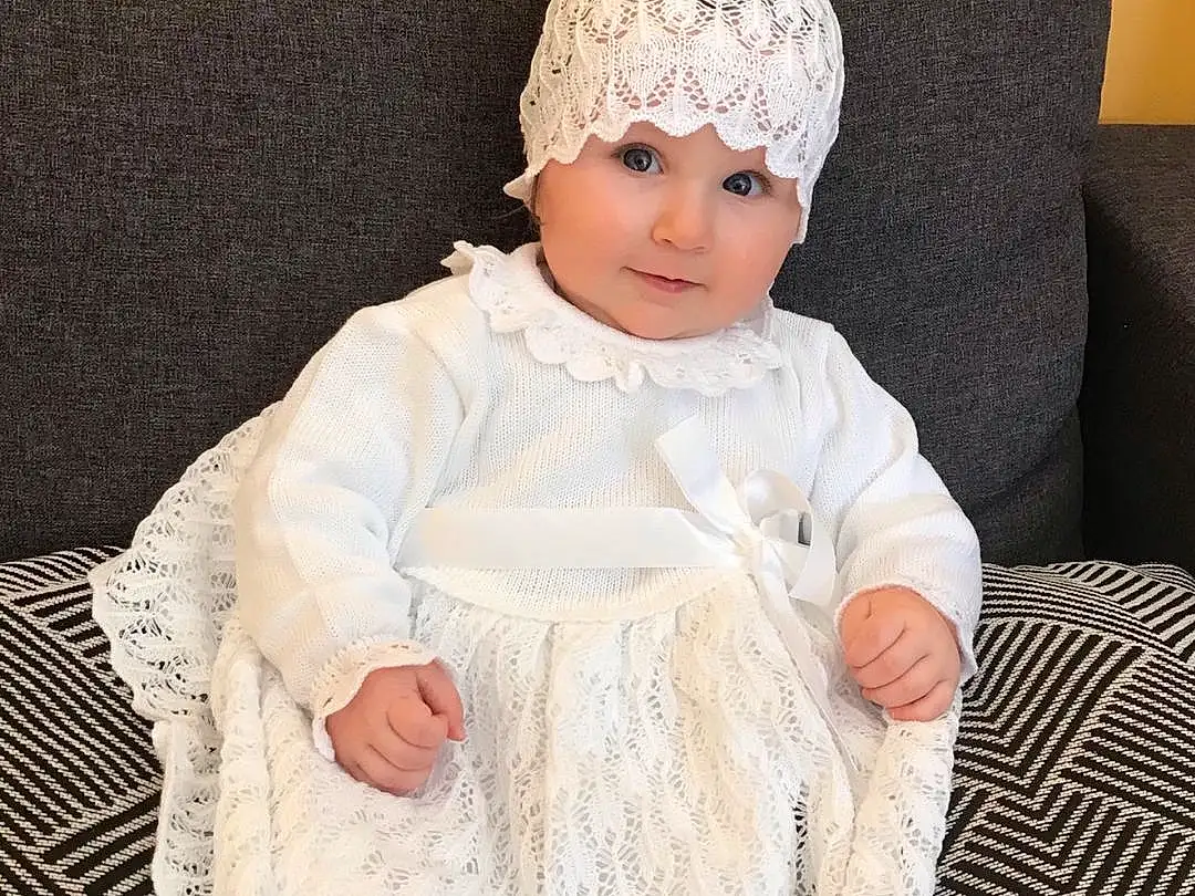 Blanc, Dress, Baby & Toddler Clothing, Textile, Sleeve, One-piece Garment, Embellishment, Bambin, Day Dress, Cap, Comfort, Fashion Design, Pattern, Wool, Assis, Enfant, Woolen, Fashion Accessory, Headpiece, Couch, Personne, Headwear