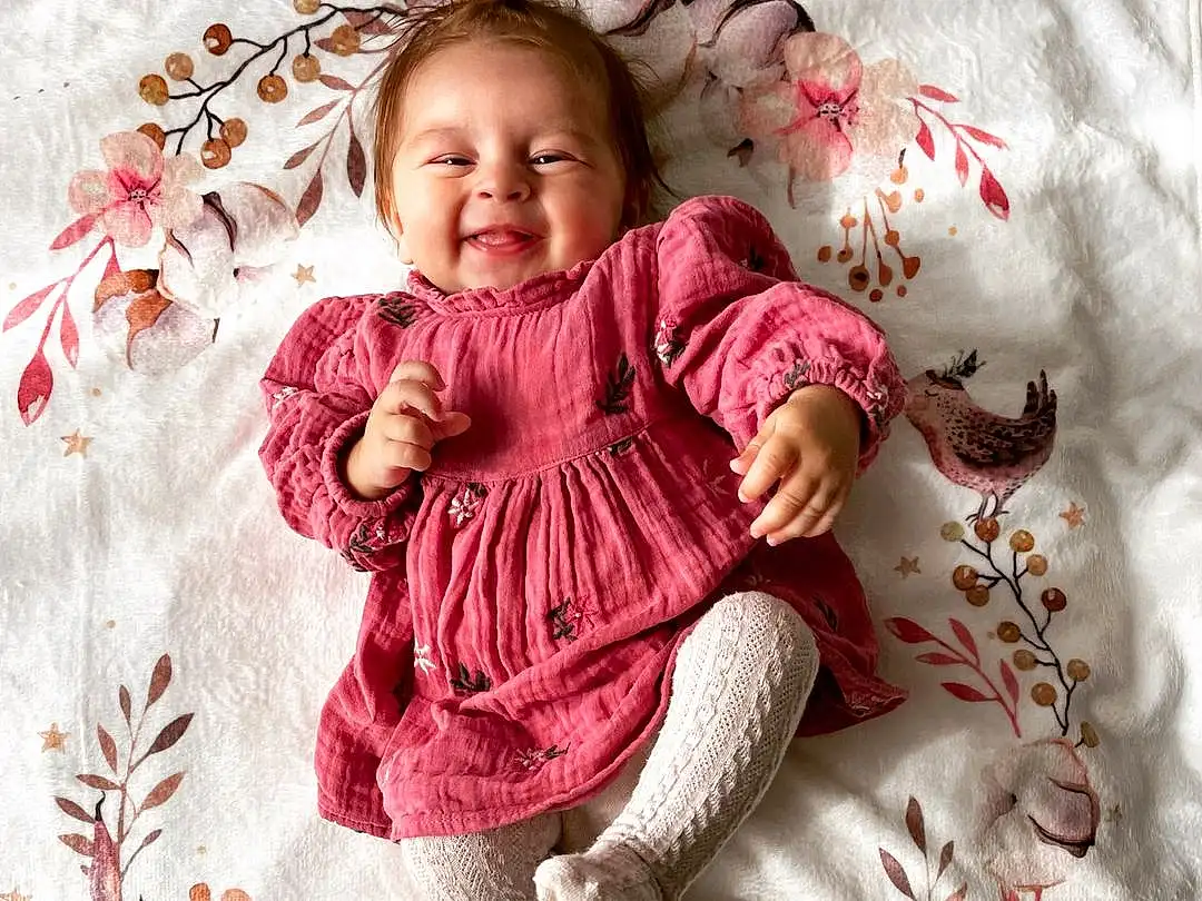 Visage, Joue, Peau, Head, Sourire, Baby & Toddler Clothing, Textile, Sleeve, Rose, Baby, Comfort, Bambin, Happy, Petal, Magenta, Pattern, Linens, Enfant, People In Nature, Assis, Personne