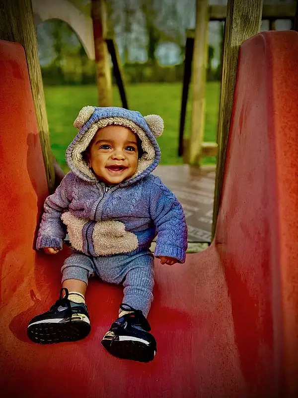 Sourire, Plante, People In Nature, Happy, Bambin, Arbre, Leisure, Bois, Fun, Baby, Recreation, Cap, Herbe, Chapi Chapo, Magenta, Hiver, Aire de jeux, Assis, Outdoor Play Equipment, Play, Personne, Joy, Headwear