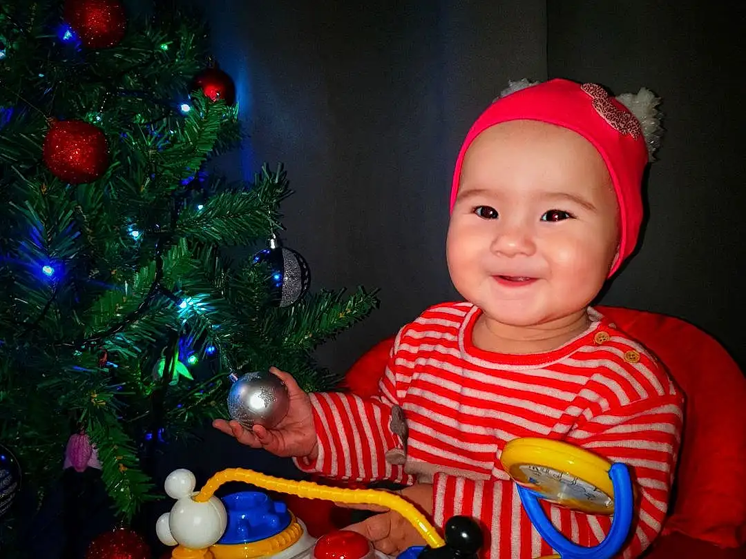 Christmas Tree, Sourire, Christmas Ornament, Human Body, Lighting, Arbre, Jouets, Ornament, Holiday Ornament, Table, Baby & Toddler Clothing, Bambin, Fun, Plante, Cap, Event, Christmas Decoration, Holiday, Enfant, NoÃ«l, Personne, Joy, Headwear
