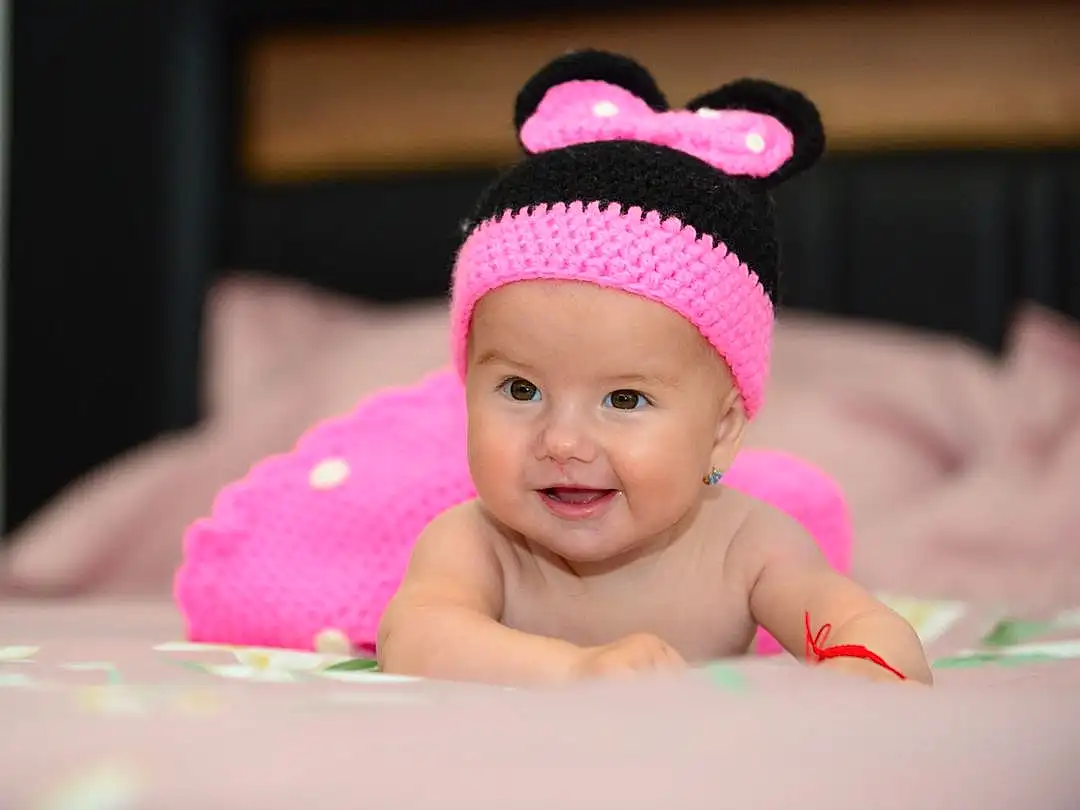 Sourire, Baby, Rose, Happy, Headgear, Bambin, Cap, Baby & Toddler Clothing, Magenta, Fashion Accessory, Sweetness, Enfant, Hair Accessory, Costume Hat, Knit Cap, Fun, Room, Portrait Photography, Laugh, Beanie, Personne, Joy, Headwear