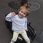 Jambe, Sourire, Road Surface, Asphalt, Gesture, Flash Photography, Happy, Sneakers, Bambin, Baby & Toddler Clothing, Human Leg, Automotive Wheel System, Street Fashion, Road, Auto Part, Assis, Recreation, Walking, Sidewalk, Luggage And Bags, Personne, Joy
