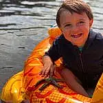 Sourire, Eau, Yeux, Facial Expression, Boats And Boating--equipment And Supplies, Orange, Lifejacket, Yellow, Lake, Vehicle, Recreation, Happy, Personal Protective Equipment, Fun, Bambin, Leisure, Enfant, Assis, Tubing, Personne, Joy