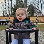 Clothing, Visage, Head, Yeux, Black, Human Body, Arbre, Swing, Sleeve, Baby & Toddler Clothing, Herbe, Baby, Bambin, Jacket, Public Space, Leisure, Happy, City, Ciel, Personne