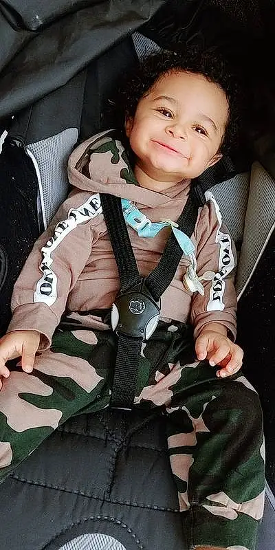 Visage, Peau, Sourire, Gesture, Flash Photography, Comfort, Bag, Bambin, Auto Part, Baby, Thumb, Car Seat, Baby Carriage, Enfant, Happy, Personal Protective Equipment, Camouflage, Baby Products, Fashion Accessory, Nail, Personne, Joy
