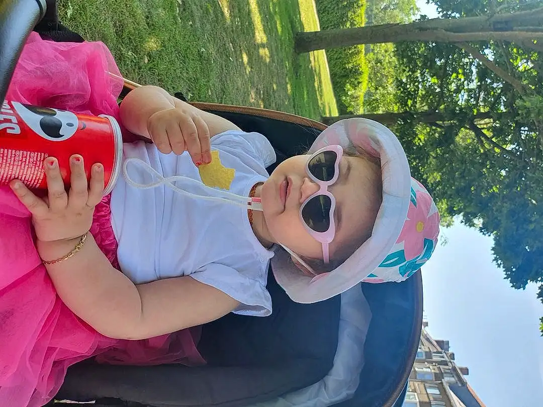 Mouth, Arbre, Happy, Gesture, Rose, Leisure, Eyewear, Fun, Recreation, Herbe, Event, Enfant, Spring, Sunglasses, Chapi Chapo, Assis, Vacation, Bambin, Jouets, Sandal, Personne