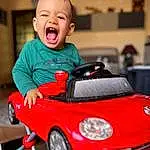 Wheel, Tire, Photograph, Sourire, Vehicle, Riding Toy, Vrouumm, Automotive Lighting, Orange, Automotive Design, Happy, Jouets, Baby & Toddler Clothing, Bambin, Red, Automotive Tire, Baby, Enfant, Rim, Personne