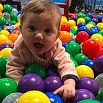 Ball Pit, Photograph, Facial Expression, Jouets, Sourire, Yellow, Leisure, Public Space, Baballe, Baby, Bambin, Fun, Enfant, Aire de jeux, Human Settlement, Baby Playing With Toys, Event, Recreation, Personne, Surprise