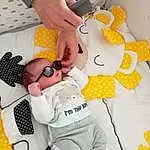 Hand, Textile, Yellow, Gesture, Jouets, Finger, Stuffed Toy, Eyewear, Nail, Linens, Font, Pattern, Enfant, Wrist, Room, Peluches, Sunglasses, Thumb, Baby Products, Button
